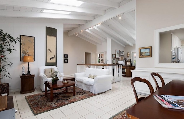 living area with lofted ceiling with skylight, track lighting, and light tile patterned floors