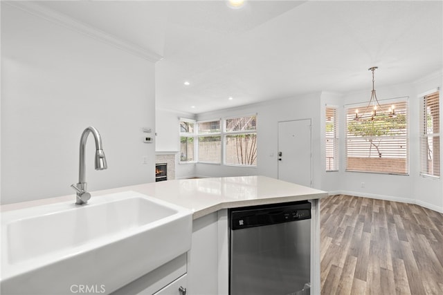 kitchen with stainless steel dishwasher, ornamental molding, sink, and hanging light fixtures