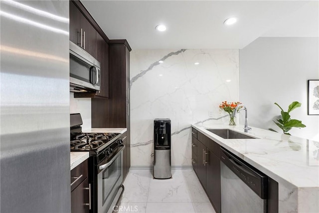 kitchen with sink, appliances with stainless steel finishes, dark brown cabinets, and light stone countertops