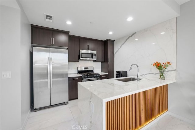 kitchen with stainless steel appliances, dark brown cabinetry, decorative backsplash, sink, and kitchen peninsula