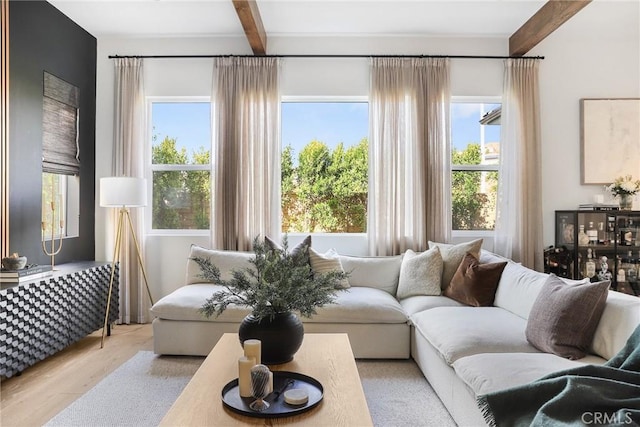 living area with beamed ceiling and light wood-style flooring