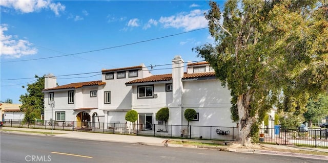 view of front of property with fence, a chimney, and stucco siding