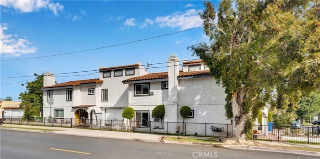 view of front of house with a fenced front yard, a chimney, and stucco siding