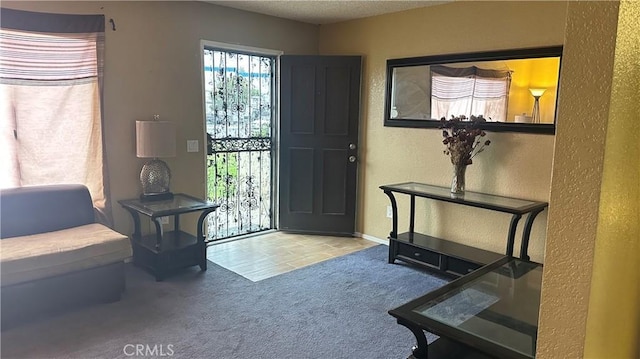 foyer entrance featuring carpet floors, a textured wall, and a textured ceiling