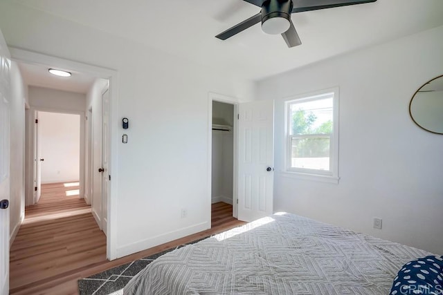 bedroom featuring a ceiling fan, a closet, baseboards, and wood finished floors