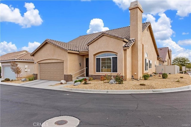 mediterranean / spanish home featuring an attached garage, stucco siding, concrete driveway, a chimney, and a tile roof