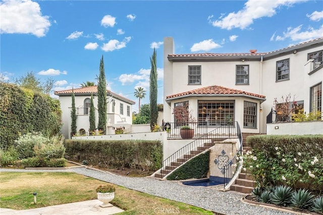 1205 W Highland Ave, Redlands, CA 92373 - rear view of house with stairway, stucco siding, a tiled roof, a chimney, and a lawn