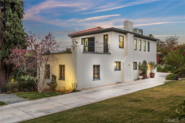 1205 W Highland Ave, Redlands, CA 92373 - mediterranean / spanish-style house with a balcony, a front yard, a chimney, and stucco siding