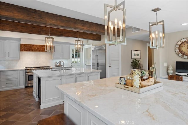 1205 W Highland Ave, Redlands, CA 92373 - kitchen with high quality appliances, a chandelier, a kitchen island with sink, tasteful backsplash, and light stone countertops