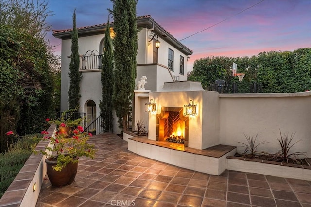 1205 W Highland Ave, Redlands, CA 92373 - back of house with a warm lit fireplace, stucco siding, a balcony, and a patio area