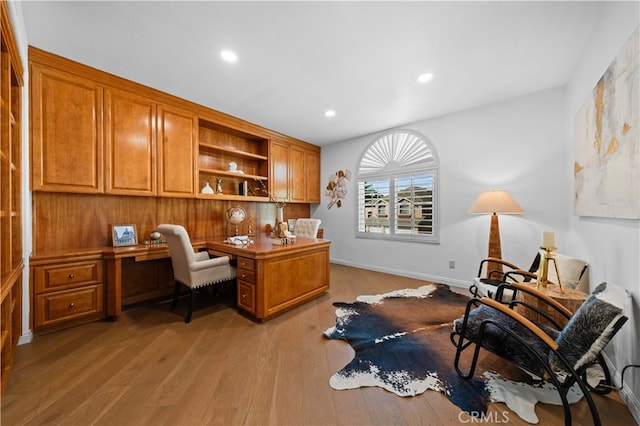 home office with light wood-style floors, recessed lighting, built in desk, and baseboards