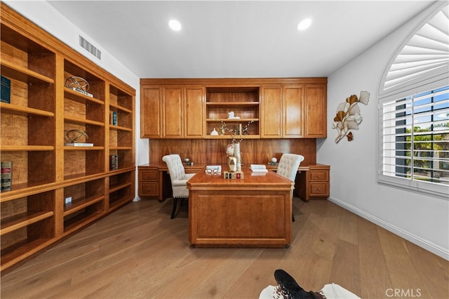 home office featuring visible vents, baseboards, built in desk, and light wood finished floors