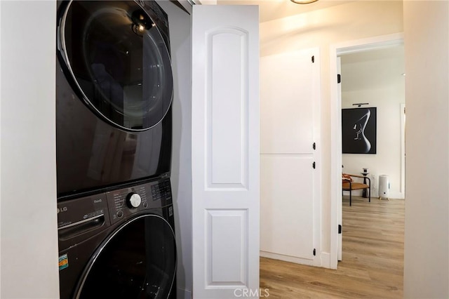 laundry room featuring light wood-type flooring and stacked washing maching and dryer