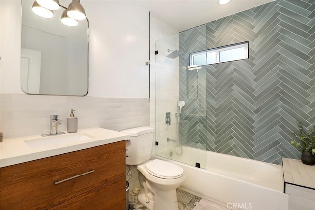 full bathroom featuring toilet, tile walls, shower / bath combination with glass door, and vanity