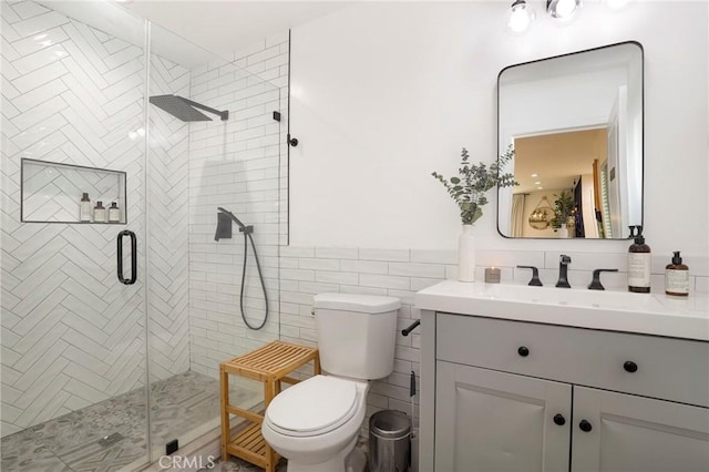 bathroom featuring toilet, tile walls, a shower with shower door, and vanity