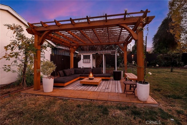 patio terrace at dusk featuring a yard, a wooden deck, a pergola, and an outdoor hangout area