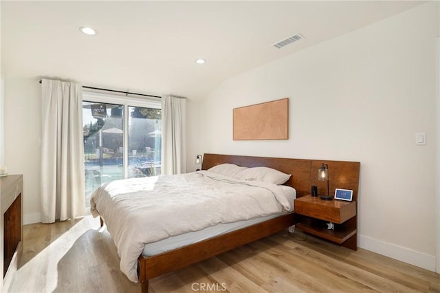 bedroom with light hardwood / wood-style floors, lofted ceiling, and access to outside