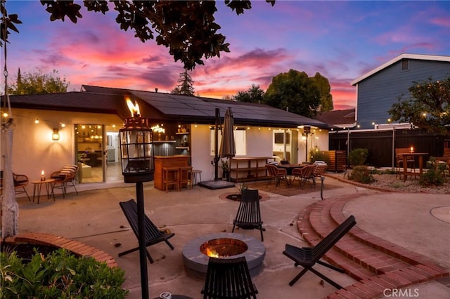 patio terrace at dusk featuring an outdoor fire pit and an outdoor bar