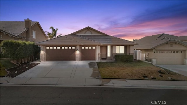 view of front of property featuring concrete driveway, stone siding, an attached garage, and a tiled roof