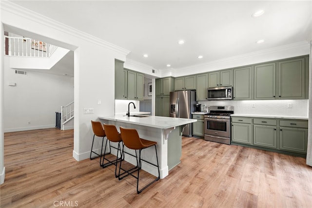 kitchen with a breakfast bar area, stainless steel appliances, a peninsula, visible vents, and green cabinetry