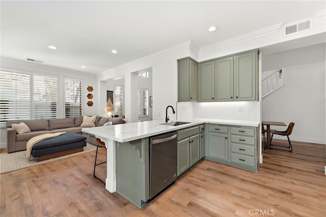 kitchen featuring a peninsula, a sink, visible vents, light wood-type flooring, and dishwasher