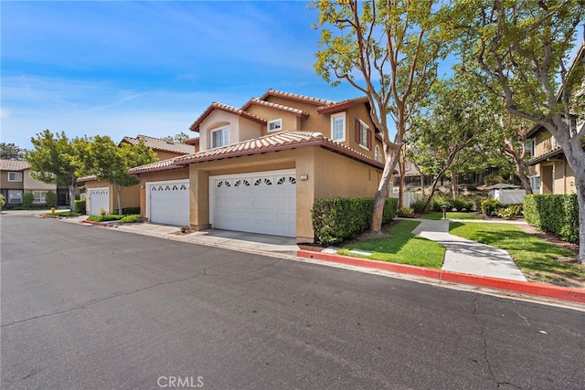 mediterranean / spanish-style house featuring a garage, a tile roof, and stucco siding