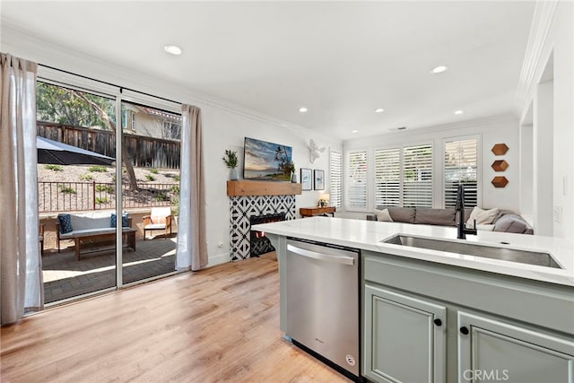 kitchen featuring crown molding, a fireplace, gray cabinetry, stainless steel dishwasher, and a sink