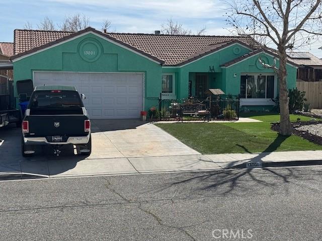 single story home featuring a tile roof, stucco siding, concrete driveway, a garage, and a front lawn