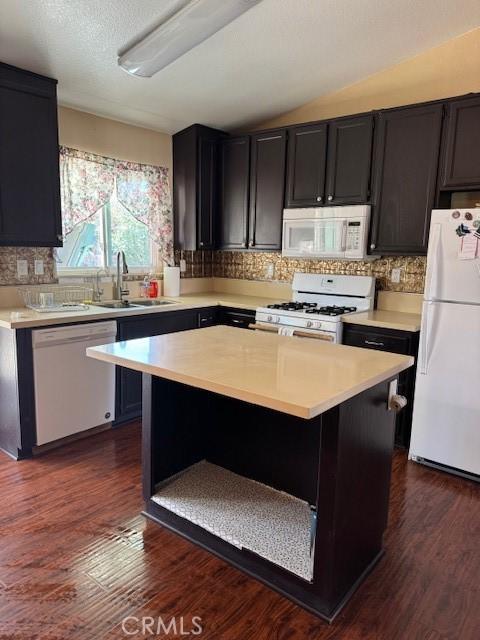 kitchen featuring a center island, light countertops, dark wood-type flooring, a sink, and white appliances