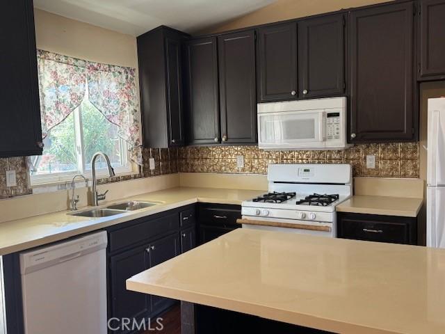 kitchen with light countertops, white appliances, a sink, and tasteful backsplash