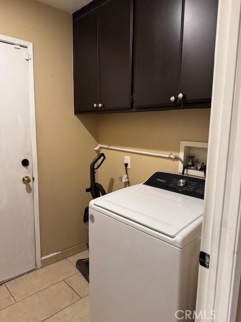 laundry area featuring light tile patterned floors, washer / clothes dryer, and cabinet space