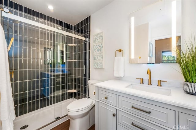 bathroom featuring a tile shower, vanity, and toilet