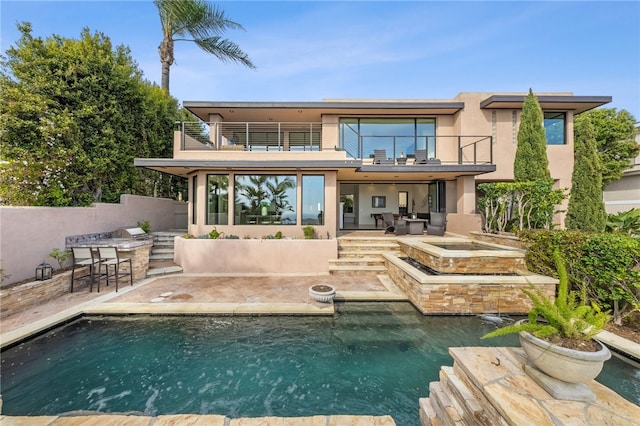 back of property with a patio area, a bar, a balcony, and a pool with hot tub