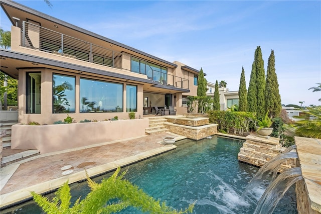 rear view of house featuring a patio area, a pool with hot tub, a balcony, and pool water feature