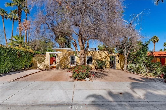 view of front of house featuring driveway, fence, and stucco siding