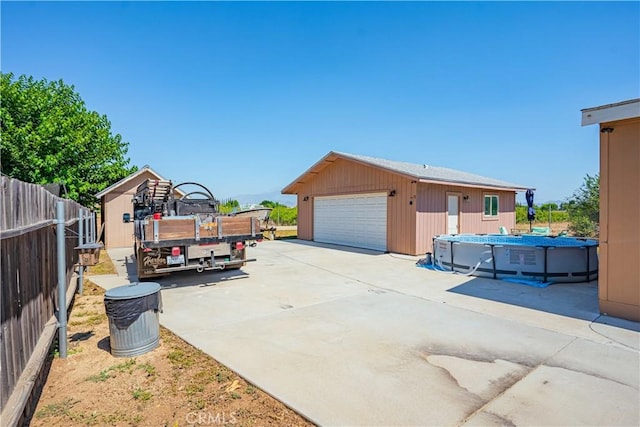 view of side of property featuring a garage, fence, a fenced in pool, and an outbuilding