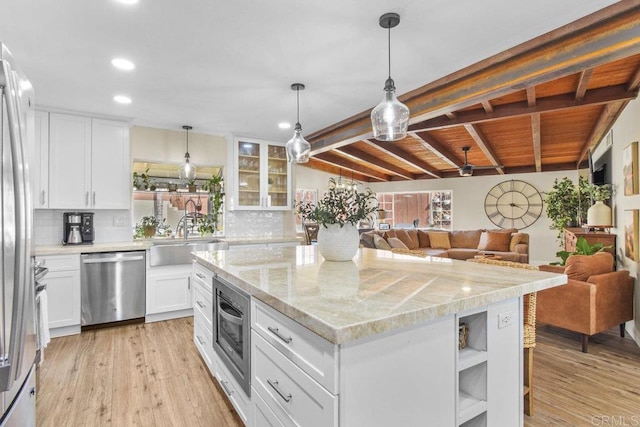 kitchen with white cabinetry, stainless steel appliances, a kitchen island, light hardwood / wood-style floors, and sink