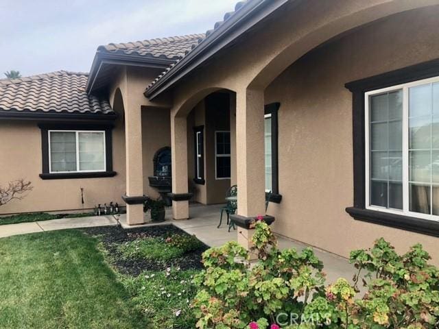 entrance to property with a lawn and a patio area