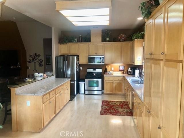 kitchen featuring appliances with stainless steel finishes, sink, vaulted ceiling, light hardwood / wood-style floors, and light brown cabinets