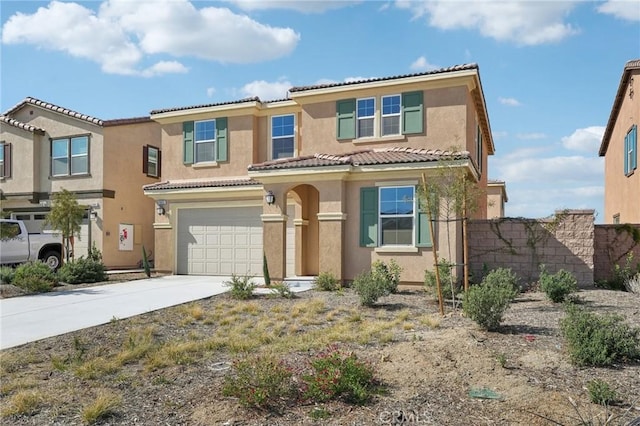 mediterranean / spanish-style home featuring driveway, a tiled roof, an attached garage, and stucco siding