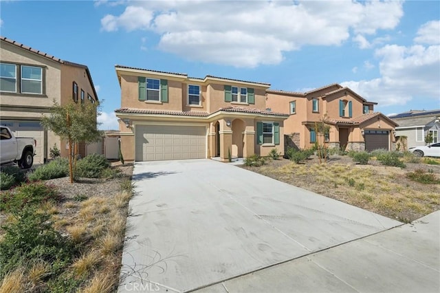 mediterranean / spanish home featuring a garage, concrete driveway, a tile roof, and stucco siding