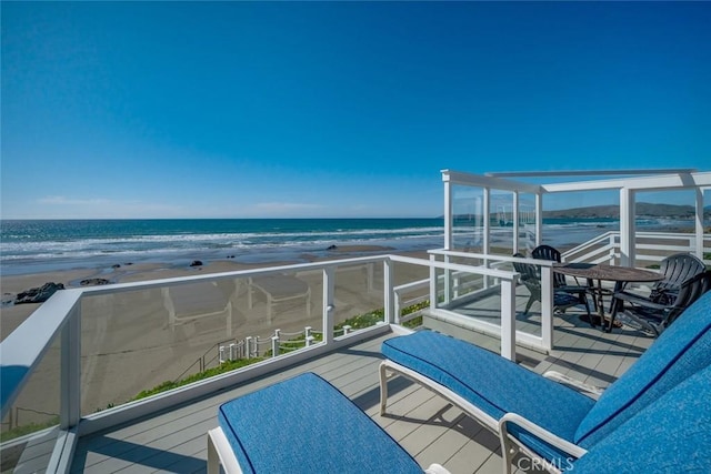 balcony with a water view and a view of the beach