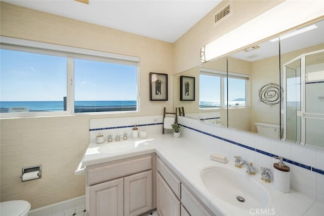 bathroom with a water view, toilet, a shower with shower door, decorative backsplash, and vanity