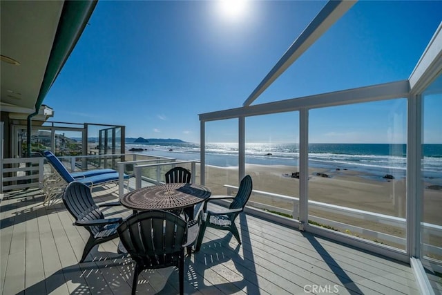 wooden terrace with a water view and a view of the beach