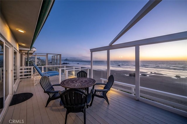 deck at dusk with a water view and a beach view