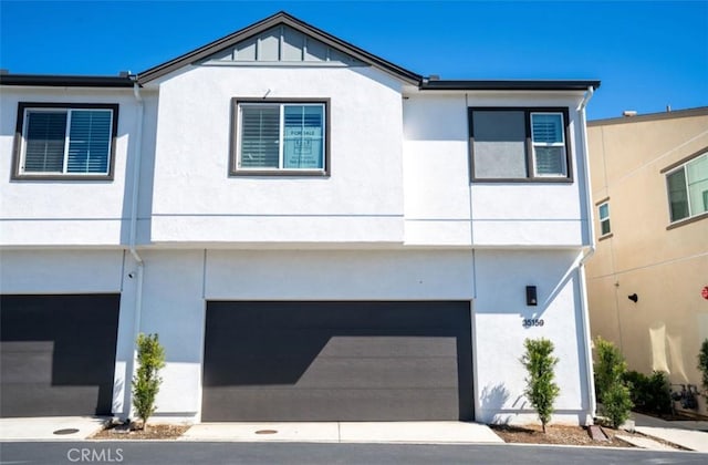 view of front facade with a garage, aphalt driveway, and stucco siding