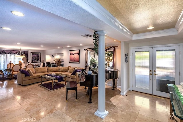 foyer entrance featuring a healthy amount of sunlight, ornate columns, a tray ceiling, and french doors