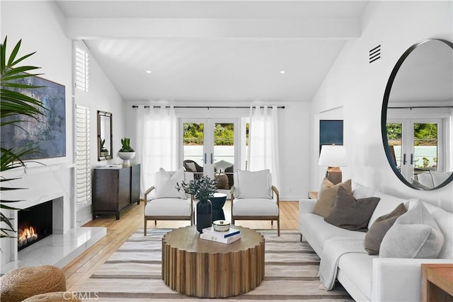 living room with light wood-type flooring, french doors, plenty of natural light, and beam ceiling