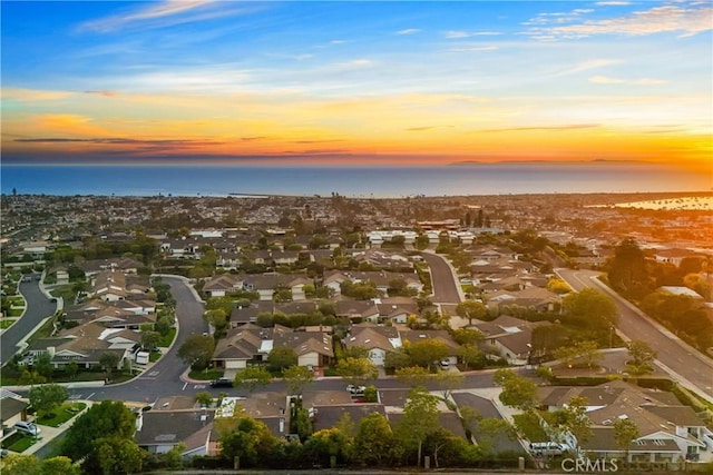 aerial view at dusk featuring a water view