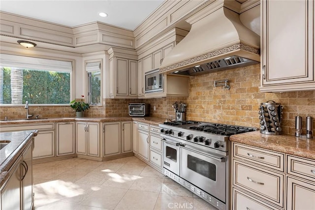 kitchen with stainless steel appliances, custom exhaust hood, cream cabinets, and sink